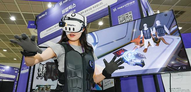 26일 서울 강남구 코엑스에서 열린 넥스트라이즈 2025에서 한 참가자가 VR 웨어러블 햅틱 기기를 체험하고 있다.