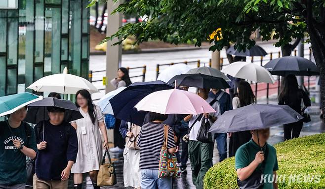 전국 대부분 지역에서 장마가 시작된 지난 20일 서울 영등포구 여의도환승센터 인근에서 시민들이 우산을 받쳐들고 출근하고 있다. 유희태 기자