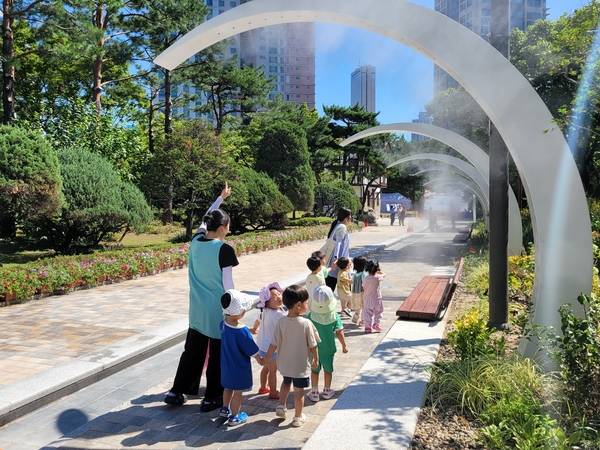 서울 영등포구 샛강역 일대의 유출지하수를 활용해 자매근린공원에 설치된 온도저감안개(쿨링포그) 아래에서 시민들이 무더위를 식히고 있다. /한국수자원공사 제공