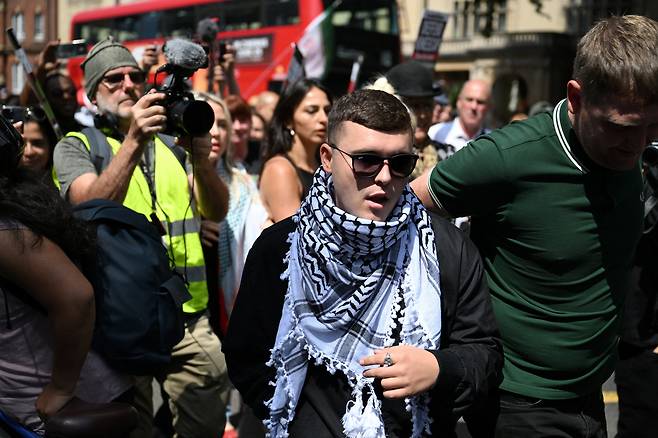 무대에서 헤즈볼라 깃발을 내걸었다는 혐의로 테러 혐의를 받은 니캡 리암 오하나(Liam Og O hAnnaidh로도 알려짐)의 멤버이자 모 차라(Mo Chara)라는 이름으로 활동하는 리암 오하나가 18일 영국 런던의 웨스트민스터 치안법원 밖에서 연설하고 있다. /연합뉴스