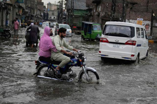 파키스탄인들이 폭우가 쏟아진 29일 동부 인도 접경 도시 라호르에서 이동하고 있다. 라호르=AP 연합뉴스