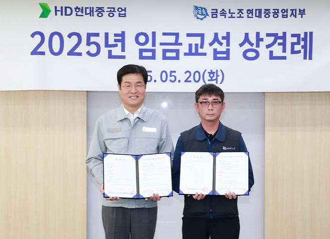 지난 5월 20일 HD현대중공업 울산본사에서 열린 ‘2025년 임금교섭 상견례’에서 이상균 HD현대중공업 사장(왼쪽)과 백호선 금속노조 현대중공업지부장이 임금교섭 기본사항 합의서를 들고 기념촬영을 하고 있다.(사진=HD현대중공업)