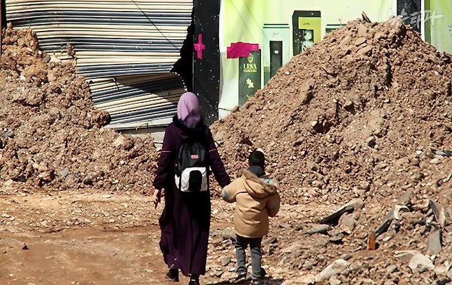 ▲제닌 난민 캠프 지역을 걷고 있는 여성과 아이 (출처: 아헤드 파크르 알딘, 마야 타반자, 란다 알와네)