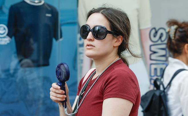 서울 최고온도 33도까지 올라 습하고 더운 날씨를 보인 2일 서울 중구 명동 거리에서 한 외국인 관광객이 손선풍기로 더위를 피하고 있다.