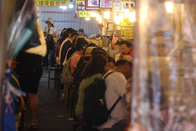 정부가 2차 추가경정예산안으로 전 국민에게 15만∼52만원씩 민생회복 소비쿠폰을 지급하기로 나선 가운데 실제 소비 진작 효과가 나타날지 이목이 쏠린다. 사진은 지난 22일 서울 남대문시장에서 시민들이 상점에서 식사를 하는 모습ⓒ 연합뉴스