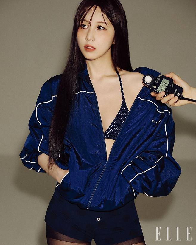 권진아가 입은 네이비 트랙 재킷은 Grand Collection by Timbershop. 네이비 도트 패턴 비키니 톱은 s/e/o. 도트 패턴의 마이크로 쇼츠는 Partimento Women.