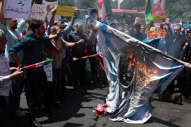 이스라엘이 이란 침공을 감행한 지 8일째 되는 2025년 6월20일, 이란 시민들이 테헤란에서 이스라엘을 규탄하며 미국과 이스라엘 국기를 불태우고 있다. AFP 연합뉴스