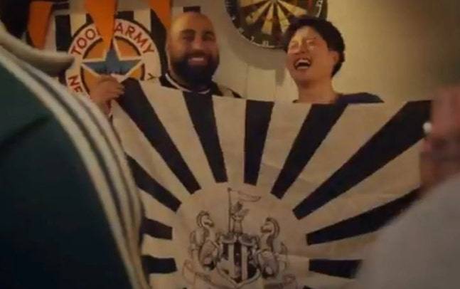 뉴캐슬이 최근 공개한 2025~2026시즌 서드 유니폼 홍보 영상에서 두 팬이 욱일기가 연상되는 문양에 뉴캐슬 구단 앰블럼이 박힌 깃발을 들고서 즐겁게 웃고 있다./사진=텔레그래프 SNS 갈무리