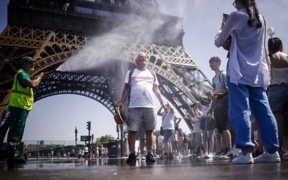 지난 1일 프랑스 파리 에펠탑 앞에서 한 관광객이 고압 호스의 물로 더위를 식히고 있다. EPA 연합뉴스