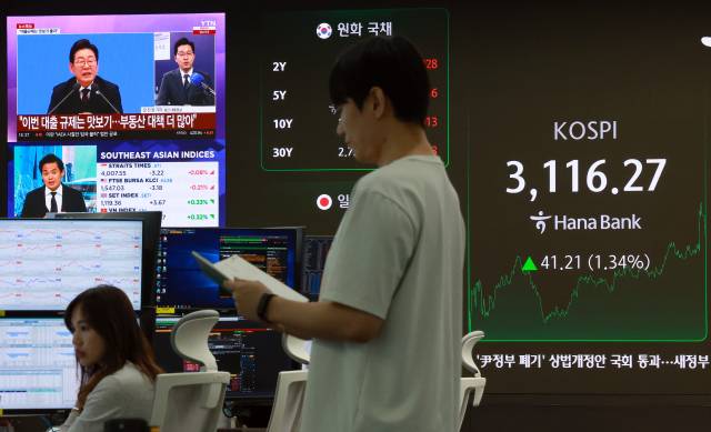 3일 서울 중구 하나은행 본점 딜링룸에서 딜러들이 업무를 보는 가운데 디스플레이에 이재명 대통령의 취임 30일 기자회견 관련 보도가 나오고 있다. 이날 코스피는 전 거래일보다 41.21p(1.34%) 오른 3,116.27로 마감했다. 원/달러 환율은 0.7원 오른 1,359.4원, 코스닥지수는 11.16p(1.43%) 오른 793.33으로 장을 마쳤다.연합뉴스