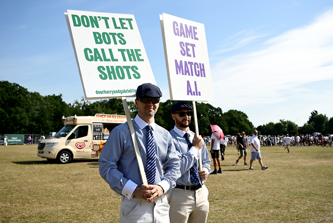지난 1일 영국 국영올잉글랜드 테니스 및 크로켓 클럽에서 사람들이 선심 복장을 입고 이번에 도입된 카메라 기반 라인 판정 기술에 반대하는 시위를 벌이고 있다. DON’T LET BOTS CALL THE SHOTS(기계에게 볼에 대한 판정을 맡기지 마라, GAME SET MATCH A.I.(게임, 세트, 매치…AI의 완승)이라는 문구가 적혀 있다. 게티이미지