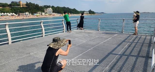 ▲ 최북단 동해안 고성군의 미항으로 불리는 아야진항 초입에는 물 위를 거닐 듯, 무지개 전망대가 힐링을 선사한다. 전망대를 찾은 연인들이 서로 사진을 찍어주고 있다.