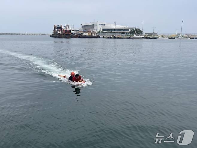지난 7일 오후 강원 속초 속초해경 전용부두 인근 해상에서 진행된 구조·구급 대응 훈련에 동참한 기자. 결국 요구조자가 돼 구조대원에 이끌려 물 밖으로 나오고 있다.(속초해경 제공, 재판매 및 DB 금지) 2025.7.8/뉴스1