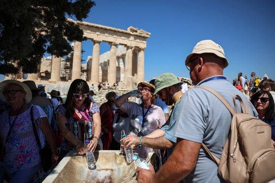 7일(현지시간) 그리스 수도 아테네의 대표적인 관광 명소 아크로폴리스를 방문한 관광객들이 40도를 넘는 폭염에 물로 더위를 식히고 있다. 로이터=연합뉴스
