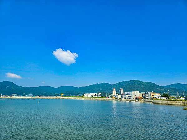 거제면의 건물 뒤로 대봉산이 펼쳐져 있고 그 오른쪽 너머로 백암산, 가운데 대봉산 자락 너머로 산방산 암봉 끄트머리가 보인다.