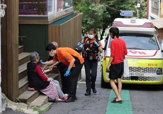 9일 서울역 앞 쪽방촌 골목에 앉아 대화하던 주민이 쓰러지자 119 구급대원들이 출동하고 있다. 연합뉸스