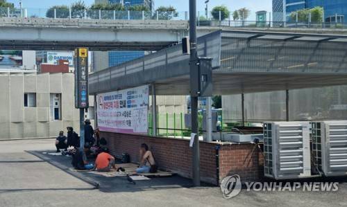 유일한 그늘 (서울=연합뉴스) 서윤호 인턴기자 = 9일 오전 서울역 2번 출구 인근에서 노숙인들이 그늘가에 앉아있다. 2025.7.9