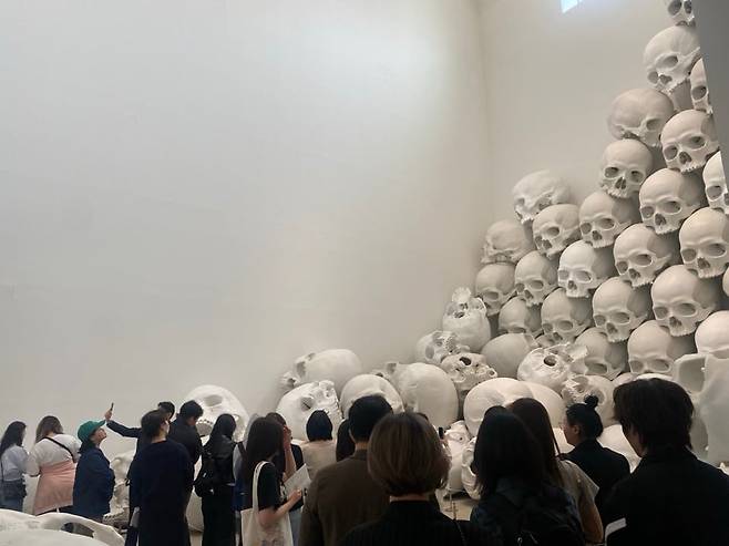 론 뮤익의 설치 작품 '매스(Mass)'를 감상하는 관람객들. 층고 14m 지하 전시장에 두개골 형상 100개가 천장 창문서부터 바닥으로 쏟아져 내리듯 쌓여 있다. /국립현대미술관