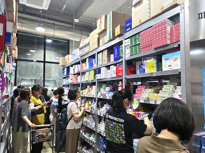 지난 3일 경기도 성남시에 위치한 메가팩토리 약국에서 방문객들이 진열대를 살펴보고 있다. 평일 낮인데도 휴대폰으로 일일이 가격을 비교하고 저렴한 제품 위주로 쓸어담는 쇼핑객들로 북적였다. <김지희 기자>