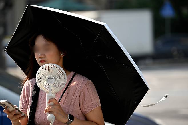 서울 지역에 폭염경보가 발효 중인 8일 오전 서울 종로구 세종대로 사거리에서 한 시민이 양산으로 뜨거운 햇살을 가리며 출근길을 서두르고 있다. 임세준 기자