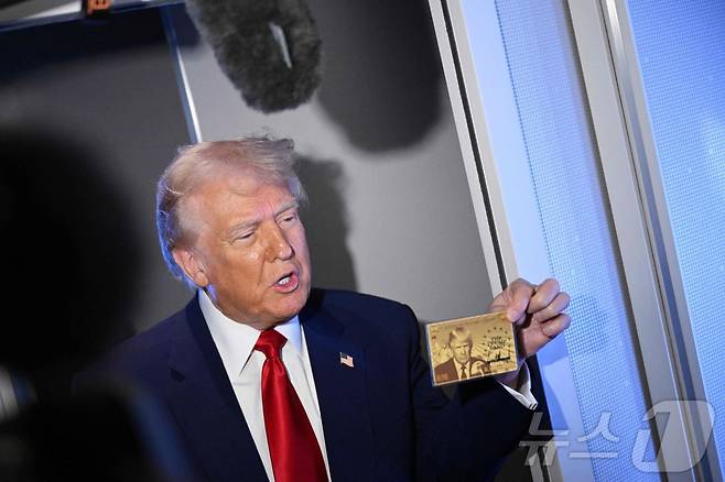 4월 3일(현지시간) 도널드 트럼프 미국 대통령이 플로리다주 마이애미로 향하는 에어포스원(미 대통령 전용기) 기내에서 기자들에게 500만 달러(약 68억 원)의 투자이민 비자 '골드 카드'를 들어 보이고 있다. 2025.04.03. ⓒ AFP=뉴스1 ⓒ News1 윤다정 기자
