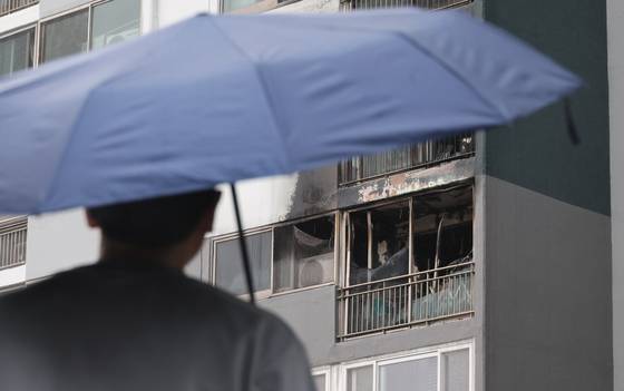 지난달 24일 오전 어린이 2명이 숨지고 다친 부산진구의 한 아파트 화재 현장에서 한 시민이 우산을 쓰고 지나고 있다. 이날 오전 4시 15분께 한 아파트 4층에서 부모가 일을 나간 사이 불이 나 10살 언니와 7살 동생이 숨졌다. 송봉근 기자