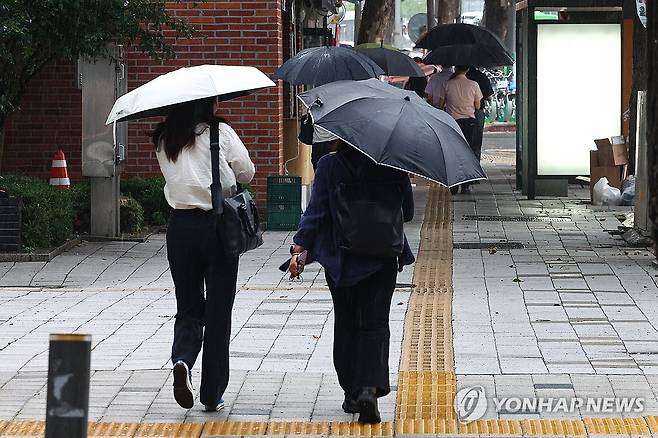폭염 달래는 소나기 (서울=연합뉴스) 서대연 기자 = 서울 최고기온이 37도까지 오르며 무더운 날씨를 보인 8일 저녁 소나기가 내리자 시민들이 우산을 쓰고 이동하고 있다. 2025.7.8 dwise@yna.co.kr