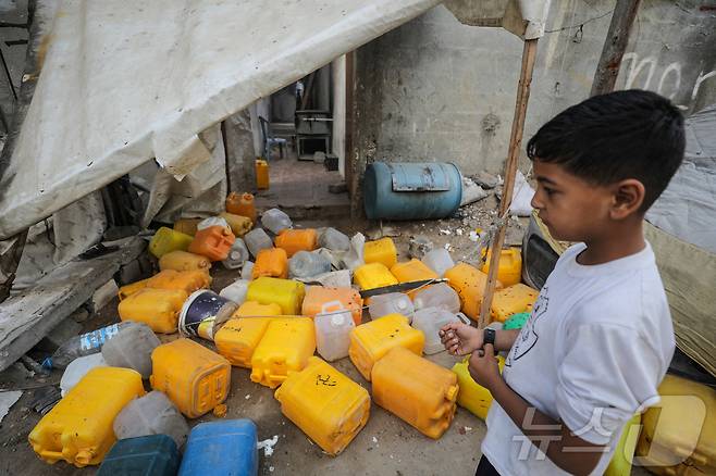 공습이 있었던 가자지구 중부 누세이랏의 급수소에서 한 팔레스타인 소년이 물통을 보고 있다.2025.07.13. ⓒ 로이터=뉴스1 ⓒ News1 유채연 기자