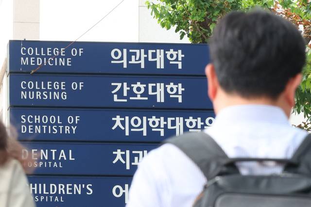 다시 학교로… : 대한의과대학·의학전문대학원학생협회 비상대책위원회가 지난 12일 전격적으로 “학교 복귀”를 선언한 가운데, 13일 서울 시내 한 대학 의과대학 표지판 앞을 한 학생이 지나가고 있다. 뉴시스