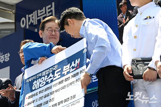 이재명 더불어민주당 대통령 후보가 14일 부산 부산진구 서면에서 열린 집중유세에서 공진완 Hmm 노조부위원장과 해양수도 부산 정책 공약 퍼포먼스를 한 뒤 악수하고 있다. 부산=류영주 기자