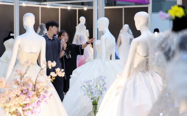 6일 서울 강남구 삼성동 코엑스에서 열린 2025 추계 웨덱스 웨딩 박람회에서 예비 부부들이 전시된 드레스를 살펴보고 있다. 사진은 기사 내용과 직접적인 관련이 없음. 뉴스1