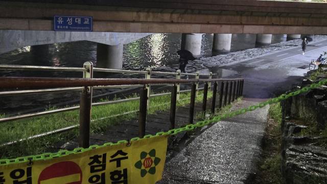 16일 오후 대전 유성대교 아래 천변. '출입통제, 침수위험'이란 문구와 함께 통제선이 설치된 진출입로 뒤에 천변을 걷는 일부 시민이 보인다. 사진=김중곤 기자