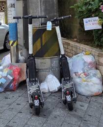 지난 14일 수영구 남천동의 한 보도에 전동킥보드가 쓰레기 더미와 함께 방치돼 있는 모습. 부산일보DB