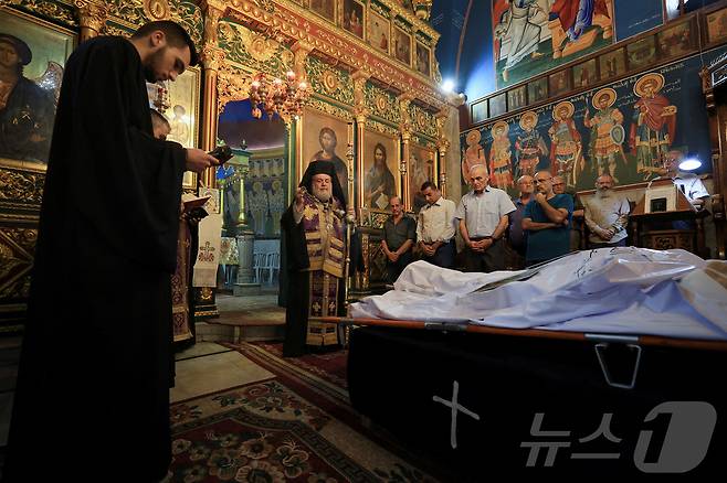 15일 알렉시오스 대주교가 가자시티의 그리스 정교회 성 포르피리우스 교회에서 슬픔에 잠긴 조문객들이 참석한 가운데, 이스라엘의 공습으로 성가족 교회에서 사망한 팔레스타인 기독교인 사드 살라마와 포우미아 아야드의 시신 앞에 서 있다. 2025.7.15 ⓒ 로이터=뉴스1 ⓒ News1 강민경 기자