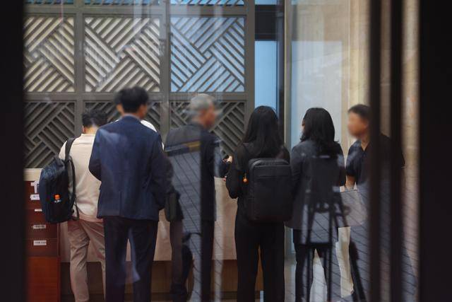 18일 김건희 여사 관련 의혹을 수사하는 민중기 특별검사팀이 압수수색을 실시한 서울 용산구 통일교 서울 본부에서 검찰 관계자들이 직원들과 대화하고 있다. 이날 특검팀은 '건진법사 청탁 의혹'과 관련해 가평에 위치한 통일교 본부와 서울 용산구에 있는 서울 본부에 대한 압수수색을 실시했다. 연합뉴스