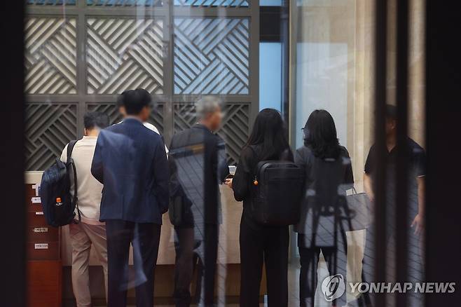 김건희 특검, 통일교 서울 본부 압수수색 (서울=연합뉴스) 김도훈 기자 = 18일 김건희 여사 관련 의혹을 수사하는 민중기 특별검사팀이 압수수색을 실시한 서울 용산구 통일교 서울 본부에서 검찰 관계자들이 직원들과 대화하고 있다.
이날 특검팀은 '건진법사 청탁 의혹'과 관련해 가평에 위치한 통일교 본부와 서울 용산구에 있는 서울 본부에 대한 압수수색을 실시했다. 2025.7.18 superdoo82@yna.co.kr