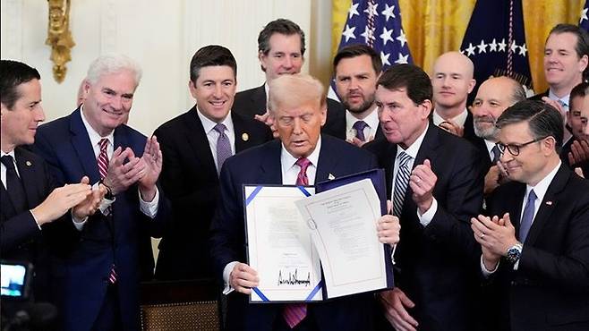 도널드 트럼프 미국 대통령이 18일(현지시간) 미 워싱턴 DC백악관 이스트룸에서 자신이 서명한 ’지니어스 법안‘을 펼쳐 보이고 있다. ⓒ AP/연합뉴스