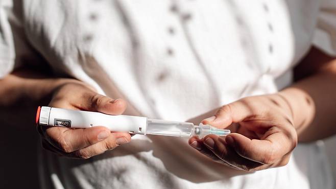 흰색 주사기펜을 들고 있는 여성의 모습