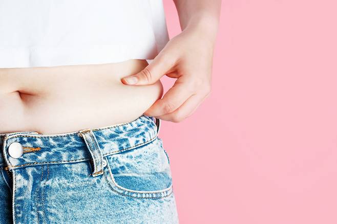 삐져나온 뱃살을 잡고 있는 모습. 셔터스톡