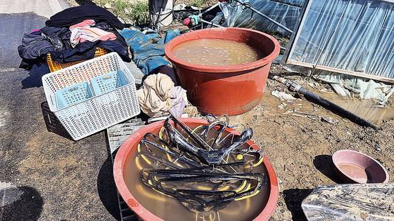 22일 오전 경남 산청군 신안면 야정마을 한 비닐하우스에서 호우 피해 주민들이 농업용 지하수 관정에서 끌어올린 물로 진흙 범벅이 된 옷가지와 옷걸이를 세척하고 있다. 단수로 가정에 물이 나오지 않아서다. 안대훈 기자