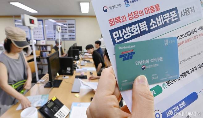 정부의 민생회복 소비쿠폰 1차 신청 첫날인 21일 경기 수원시 행궁동 행정복지센터에서 한 시민이 선불카드를 수령받고 있다. 소비쿠폰 신청은 요일제에 따라 출생 연도 끝자리 1·6은 월요일, 2·7은 화요일, 3·8은 수요일, 4·9는 목요일, 5·0은 금요일에 신청할 수 있다. 주말에는 온라인 신청만 가능하며 사용기한은 11월 30일까지다. /사진제공=뉴시스