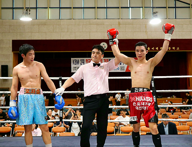 KBM 라이트급 챔피언 김종헌이 2025년 7월 서울특별시 용산구 이태원초등학교 특설링 한우리복지회회장배 프로복싱대회에서 판정 2-0 승리 및 타이틀 1차 방어 선언을 받고 있다. 사진=한국복싱커미션