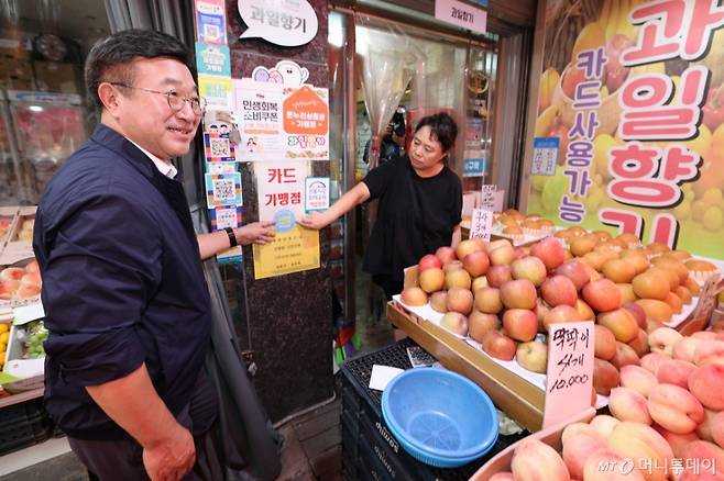 (서울=뉴스1) 오대일 기자 = 윤호중 행정안전부 장관이 24일 오후 서울 금천구 비단길 현대시장을 찾아 과일가게 상인과 함께 민생회복 소비쿠폰 사용가능 매장 스티커를 붙히고 있다. 2025.7.24/뉴스1 Copyright (C) 뉴스1. All rights reserved. 무단 전재 및 재배포, AI학습 이용 금지. /사진=(서울=뉴스1) 오대일 기자