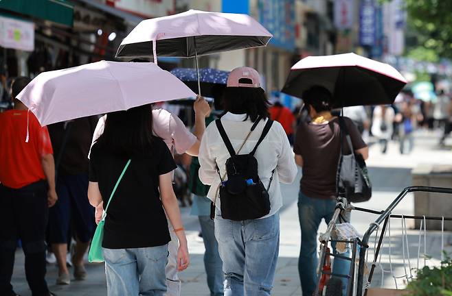 시민들이 22일 오후 서울 시내의 한 거리에서 양산으로 강한 햇빛을 피하며 걸어가고 있다. 뉴시스