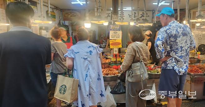 27일 정오께 찾은 수원시 팔달구 못골종합시장 내 '민생회복 소비쿠폰' 사용가능 안내문을 부착한 한 반찬가게에서 시민들이 밑반찬을 구입하고 있다. 신연경기자