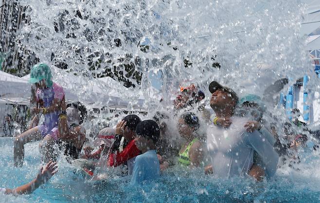 27일 서울 종로구 광화문 광장 서울썸머비치에 마련된 수영장에서 시민들과 어린이들이 폭포수를 맞으며 더위를 식히고 있다./ 뉴시스