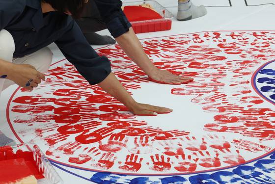 제80주년 광복절을 한 달 앞둔 15일 오후 경기 수원시 권선구청에서 구청 공무원 및 보훈단체 관계자, 권선구 리틀야구단 선수 등 참가자들이 손도장을 찍어 태극기를 만들고 있다. 뉴스1