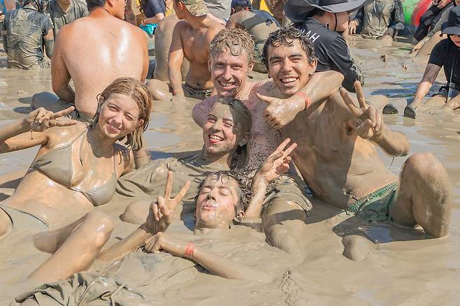 외국인 청년 관광객들이 머드탕에서 머드 마사지를 즐기는 모습. 보령시 제공