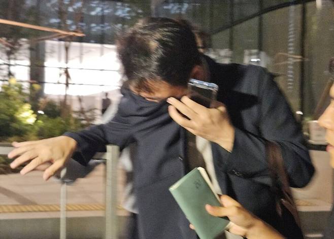 김건희 여사 오빠인 김진우씨가 28일 밤 김 여사 관련 의혹들을 수사하는 민중기 특별검사팀 사무실이 위치한 서울 종로구 케이티(KT)광화문빌딩웨스트(West)에서 조사를 마친 뒤 얼굴을 가린 채 특검 사무실을 나서고 있다. 연합뉴스