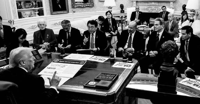 트럼프 영웅주의 면모를 부각시킨 백악관 흑백 사진 지난 22일(현지시간) 백악관에서 일본 협상팀을 앉혀두고 무역협상을 최종 타결한 도널드 트럼프 미국 대통령. 그의 책상 위 문서에도 일본이 원하는 상호관세율과 대미 투자액을 일방적으로 수정한 손글씨 수치들이 표기돼 있다. <사진=댄 스카비노 백악관 부비서실장 소셜미디어>